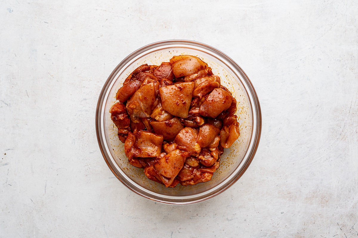 Seasoned chicken pieces in glass mixing bowl.  