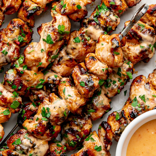 Grilled bang bang chicken skewers with bang bang sauce on the side.