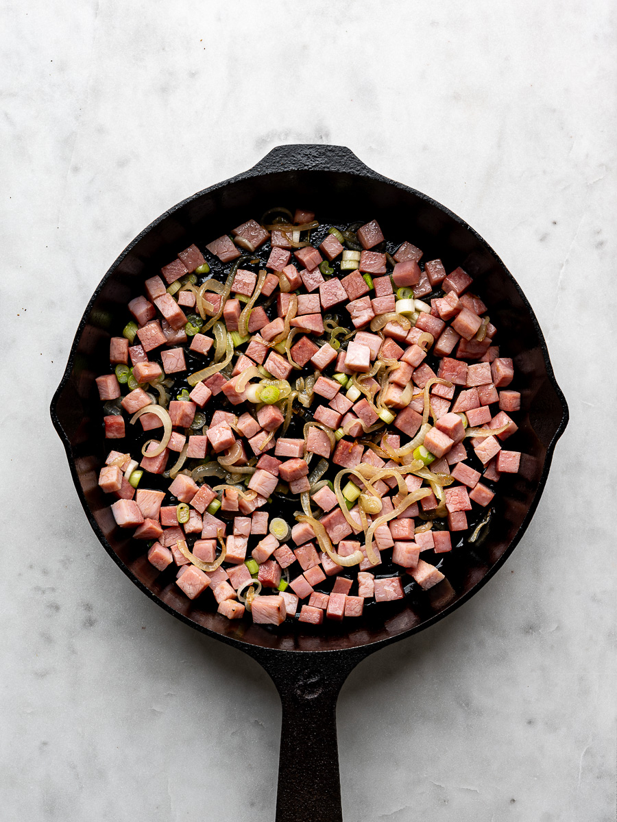 Sautéed ham and onion mixture in cast iron skillet. 