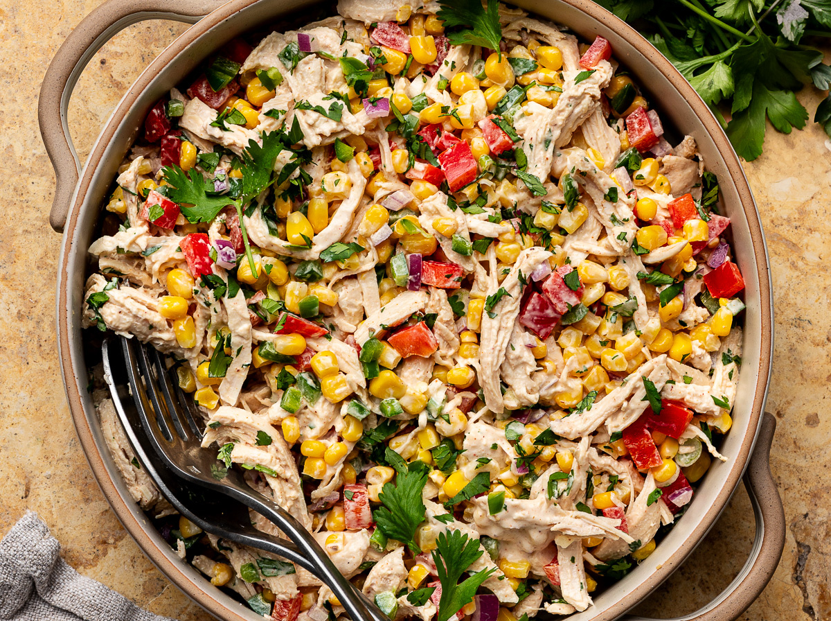 Shredded chicken chicken in a salad bowl tossed with corn, dream dressing, cilantro, jalapeños and bell pepper. 