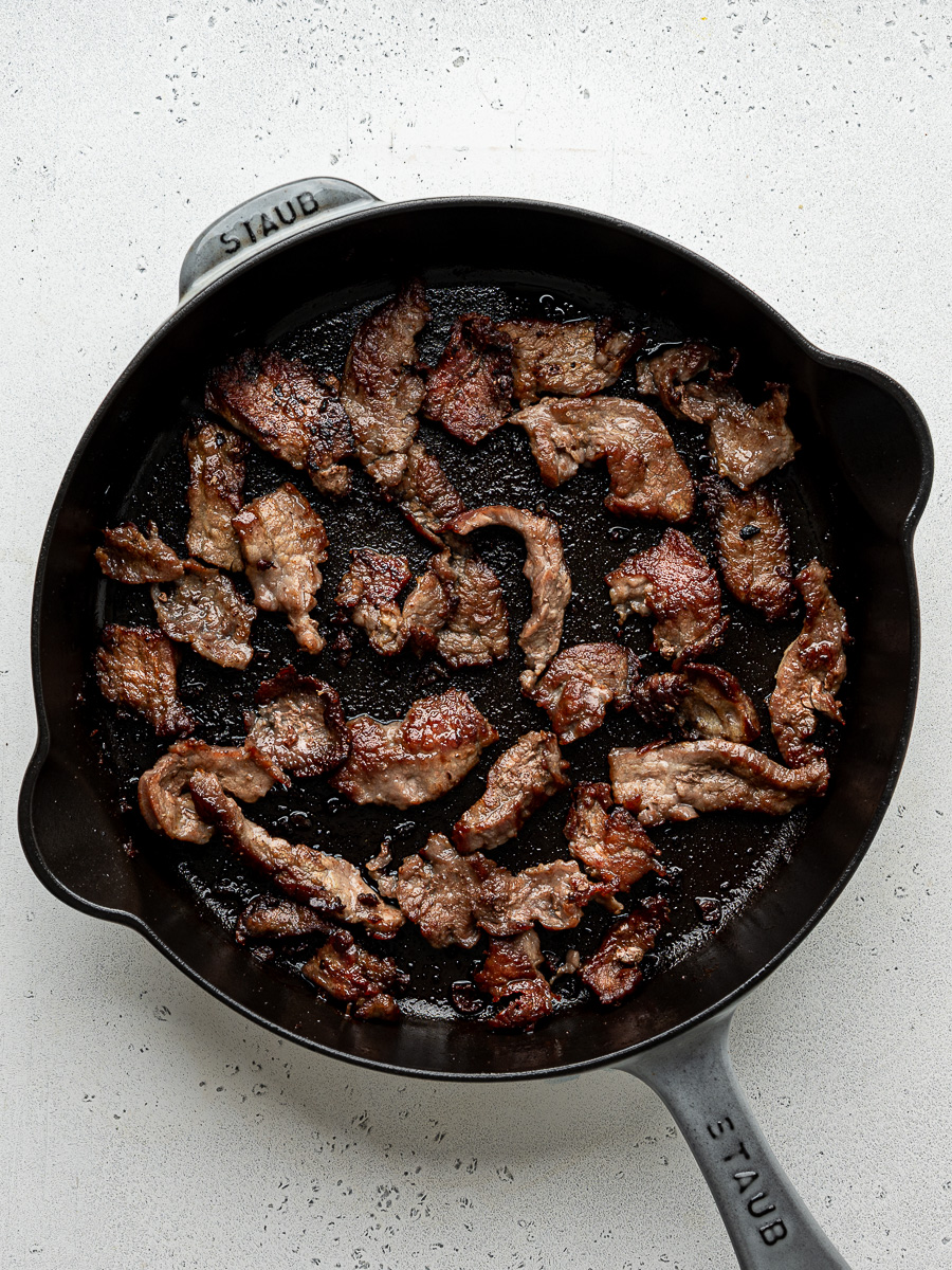Seared beef strips in skillet. 