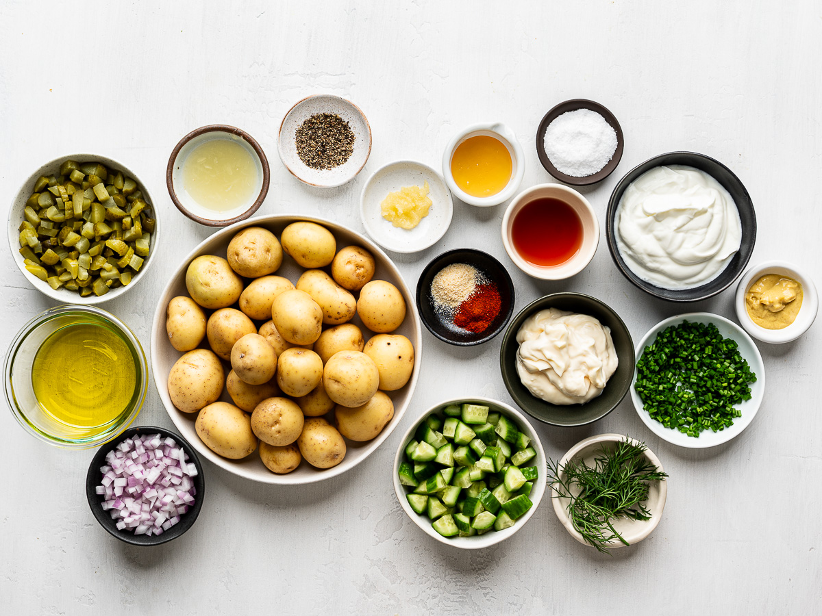 Fresh ingredients laid out for crispy smashed potato salad recipe with Greek yogurt, cucumbers, and herbs.