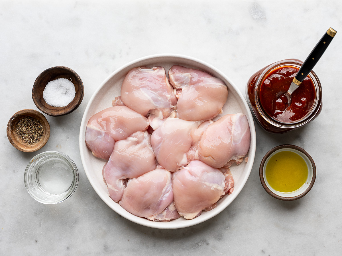 Ingredients prepared in bowls for making boneless BBQ chicken thighs on the grill.