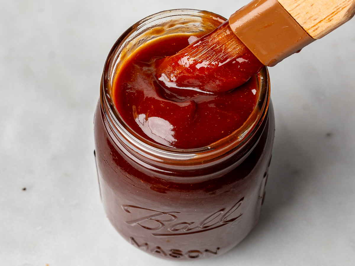 Top view of bbq sauce in mason jar with pastry brush dipped into it.