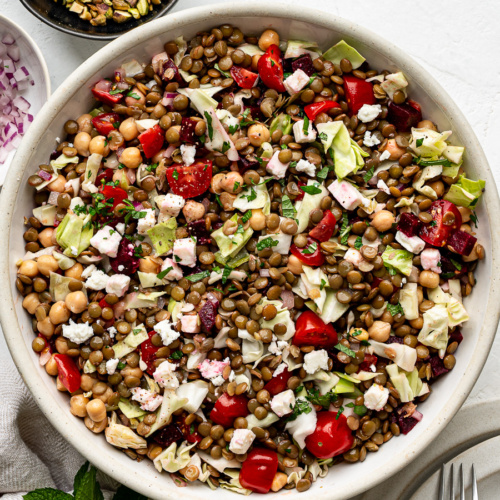 Colorful lentil chopped salad with cabbage, tomatoes, and herbs in a serving bowl — a healthy, make-ahead summer salad.