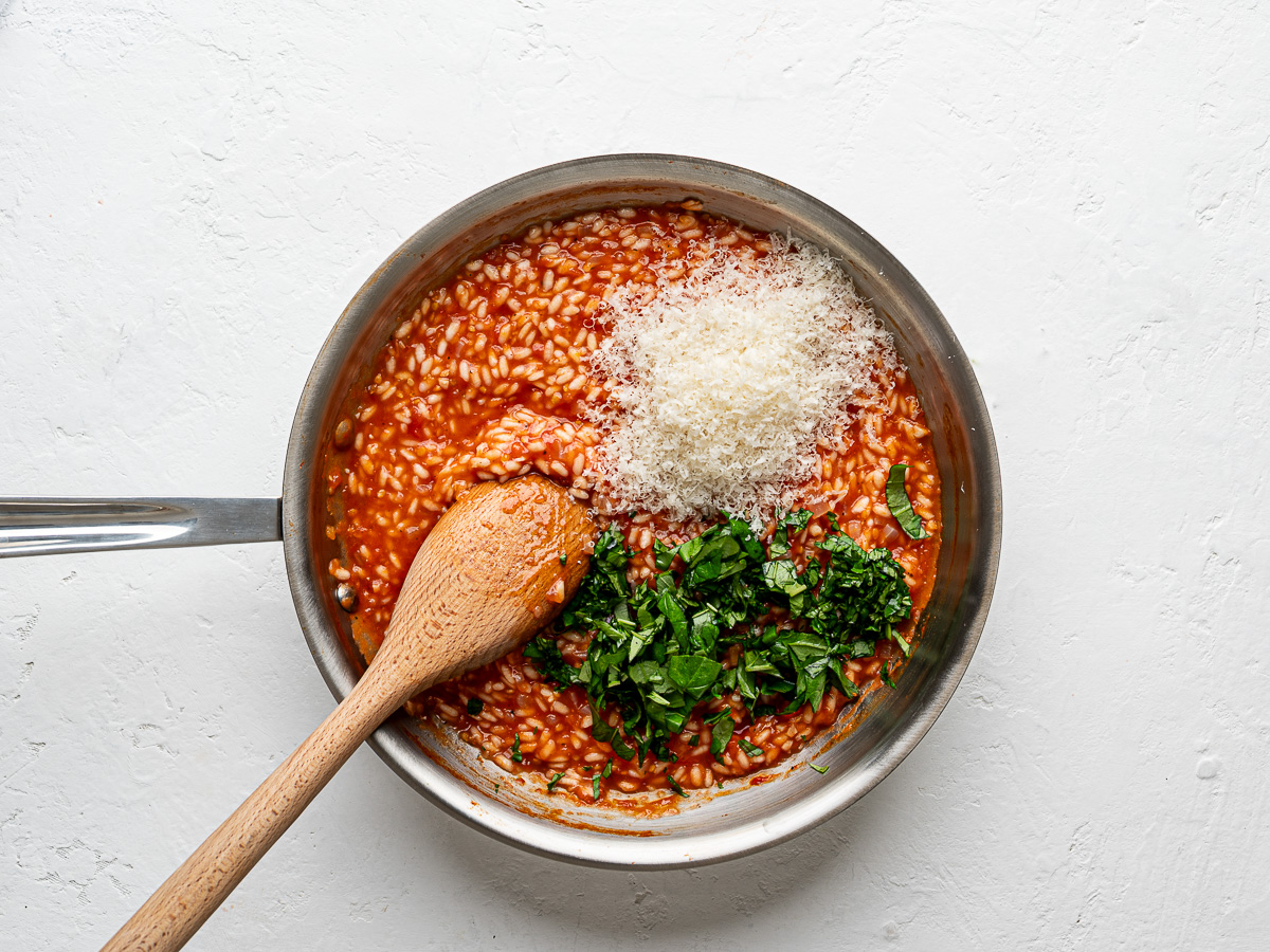 Adding parmesan cheese and chopped basil to rice mixture in skillet.