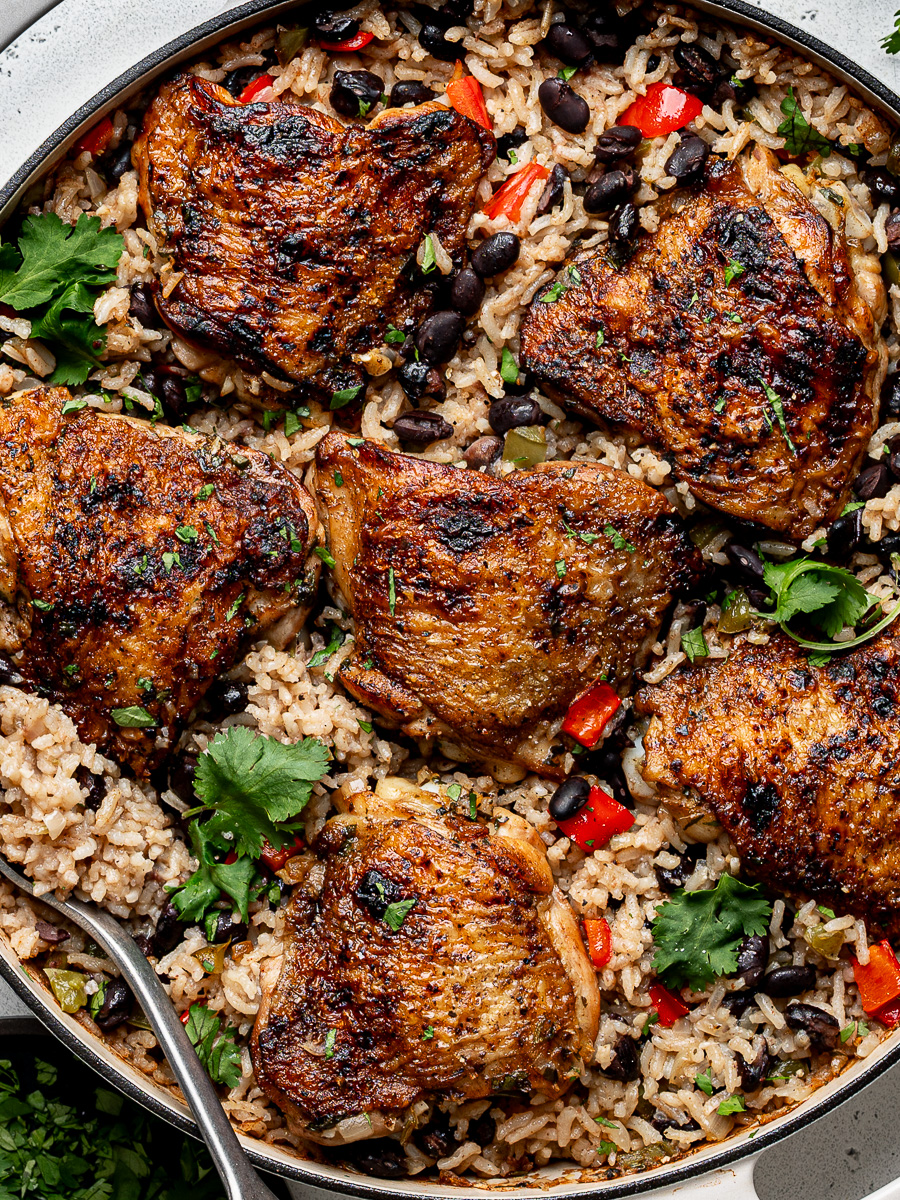 Close-up of Baked dish of chicken with rice and black beans in white skillet.