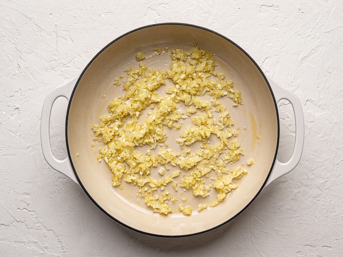 Sautéed onions and garlic in large white skillet.