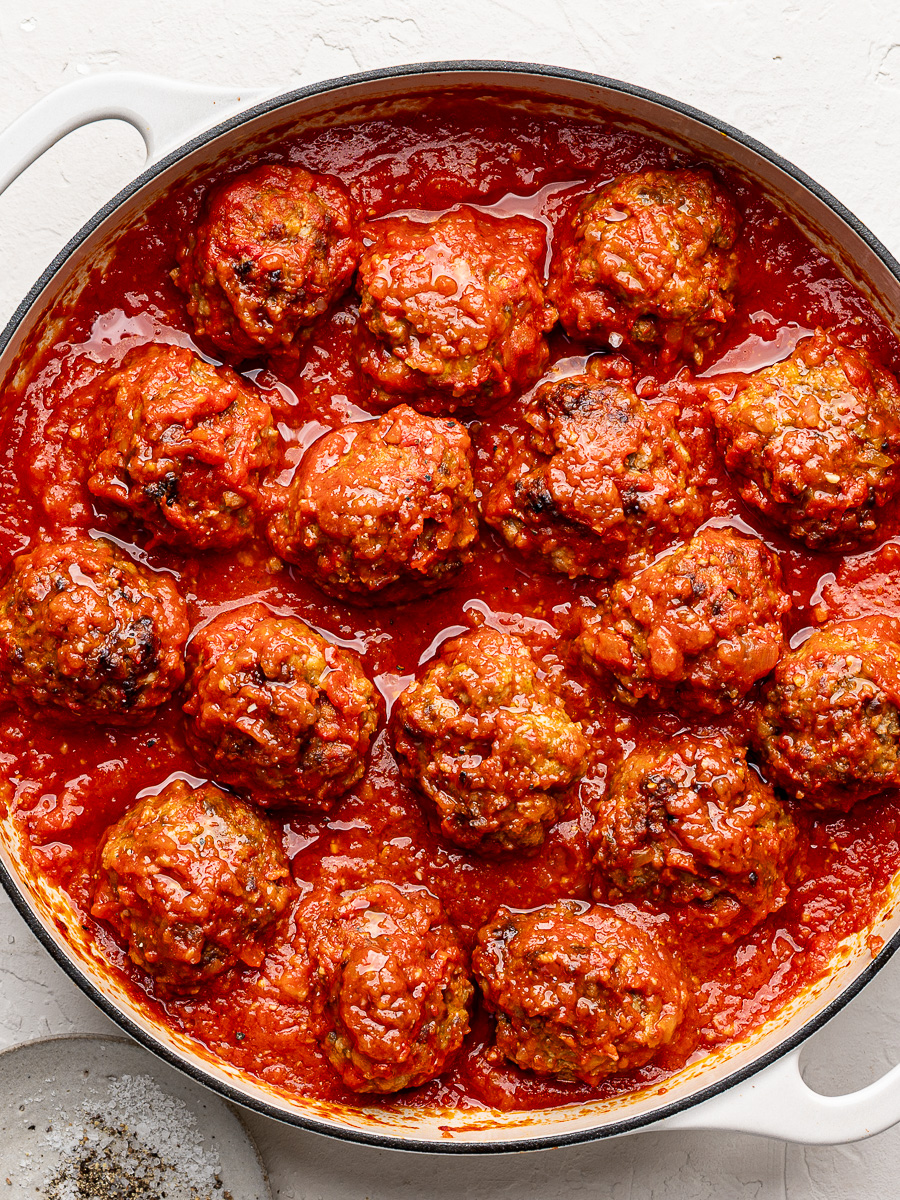 Tender ricotta meatballs in tomato sauce in large white skillet.