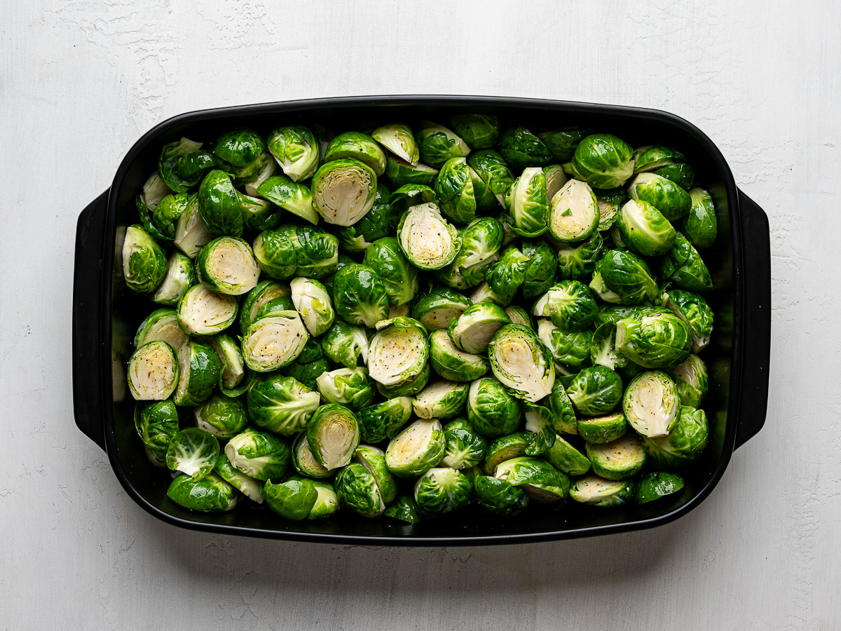 Halved Brussels sprouts in baking dish about to be roasted.
