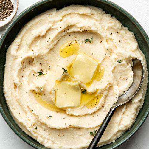 Creamy mashed potatoes with butter and herbs swerved in a green bowl.