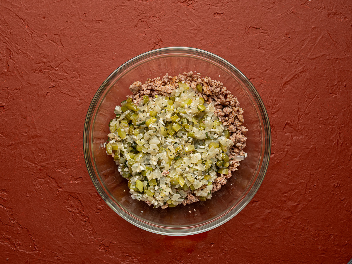 Cooked sausage and vegetable mixture in glass bowl.