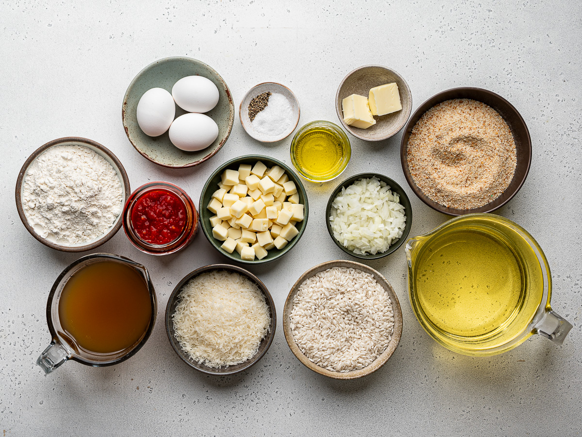 Ingredients to make Italian rice balls prepared in individual small bowls.