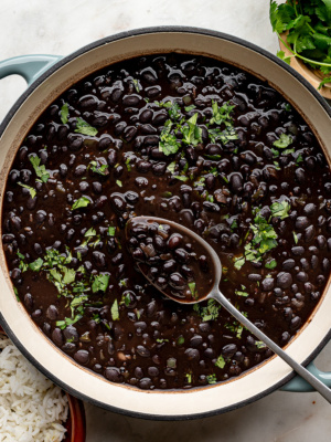 Creamy cooked canned black beans in a green skillet garnished with fresh cilantro.