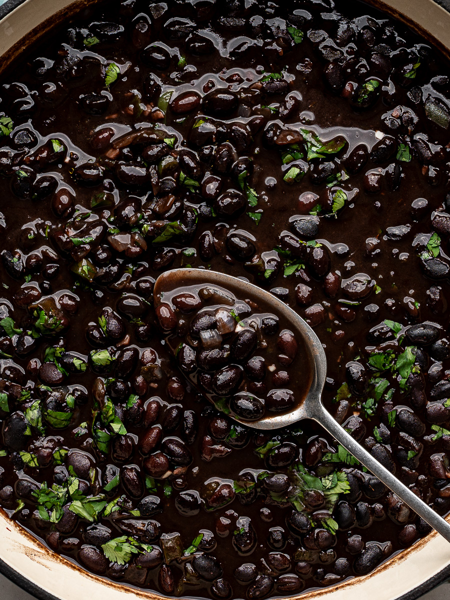 Close-up of saucy black beans cooked with spices, topped with fresh cilantro.