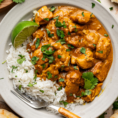 Coconut chicken curry plated with fluffy basmati rice and torn pieces of naan bread on the side, ready to serve.