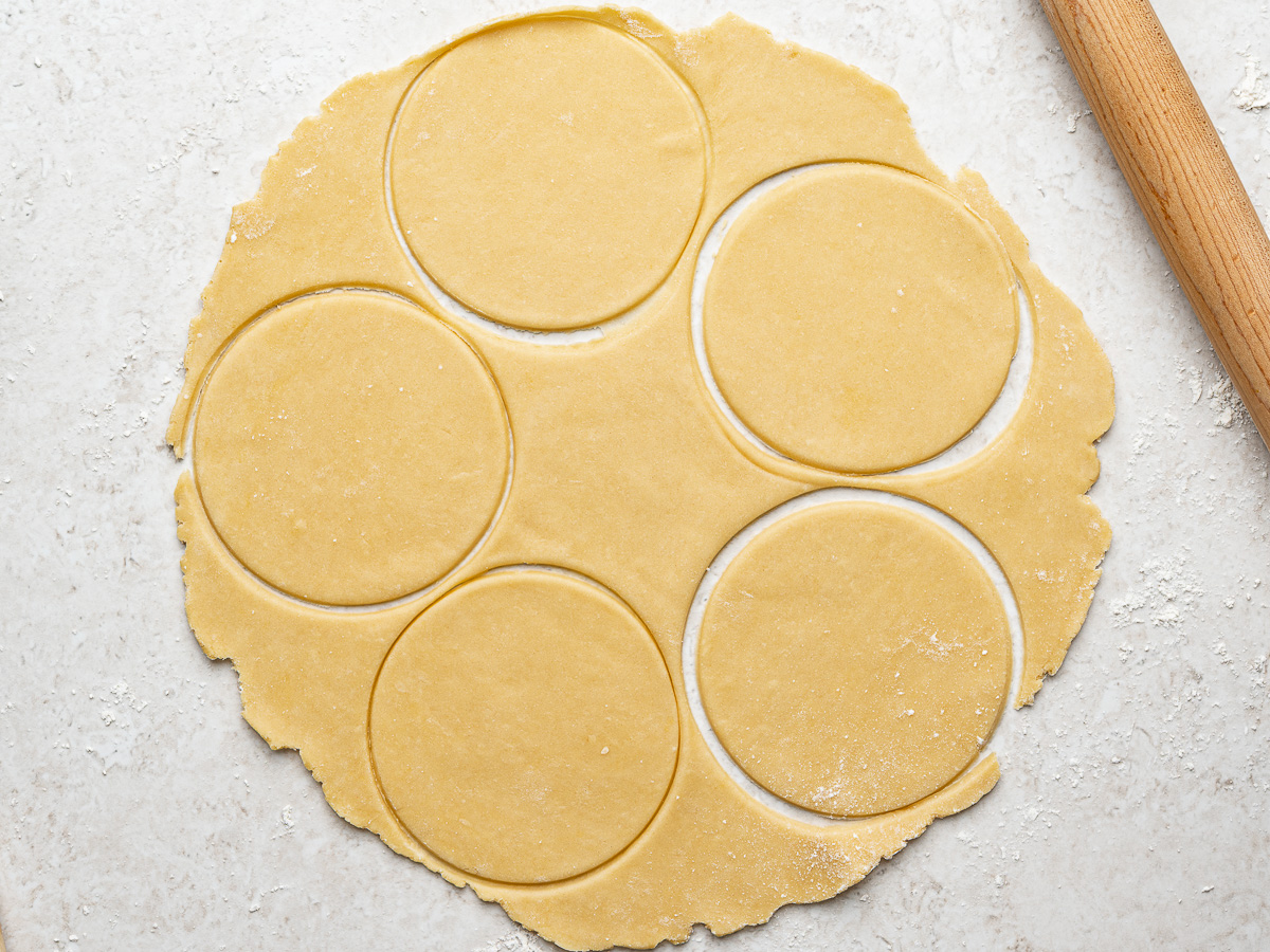 Rolled out dough with empanada discs cut out.