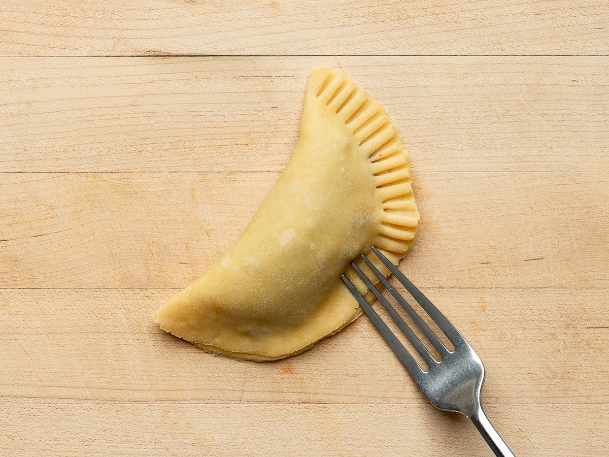Fork sealing edge of one empanada.