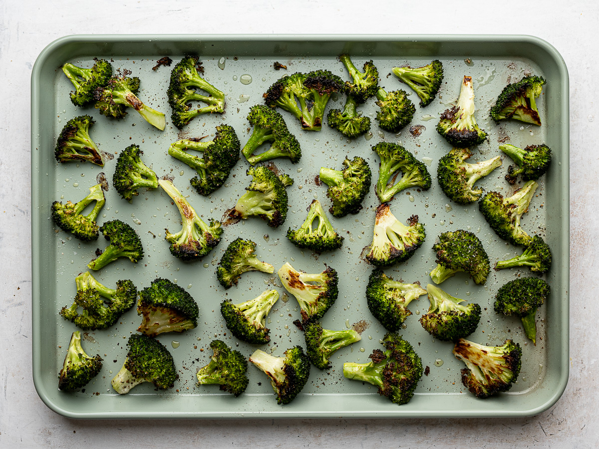 Roasted broccoli florets spread out evenly on a sheet pan.