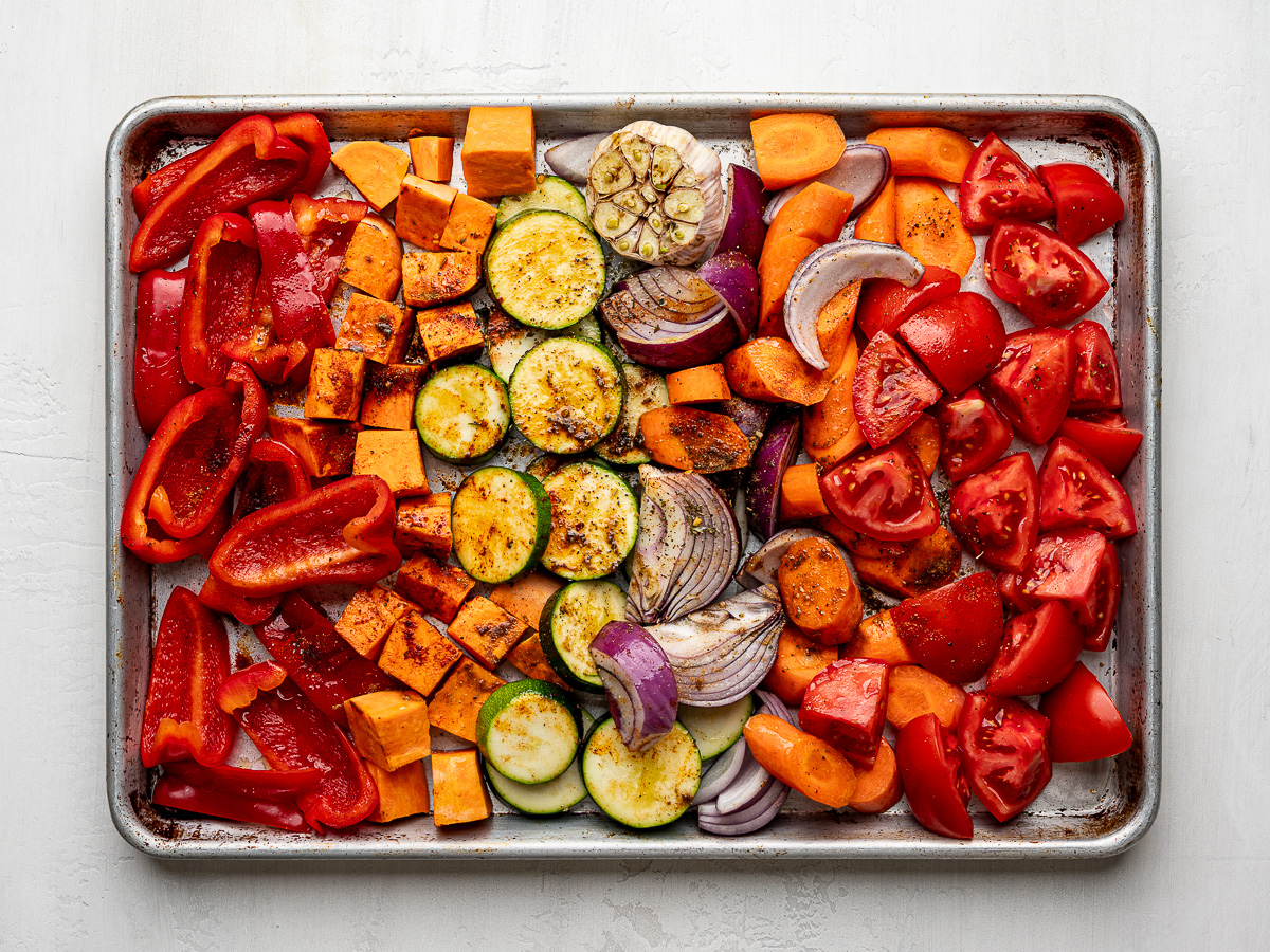 Chopped vegetables on a rimmed sheet pan, seasoned and ready to roast for sheet pan vegetable soup.
