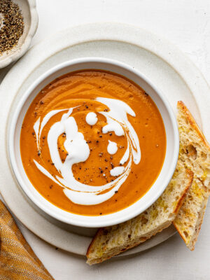 Bowl of roasted vegetable soup with toasted bread on the side.