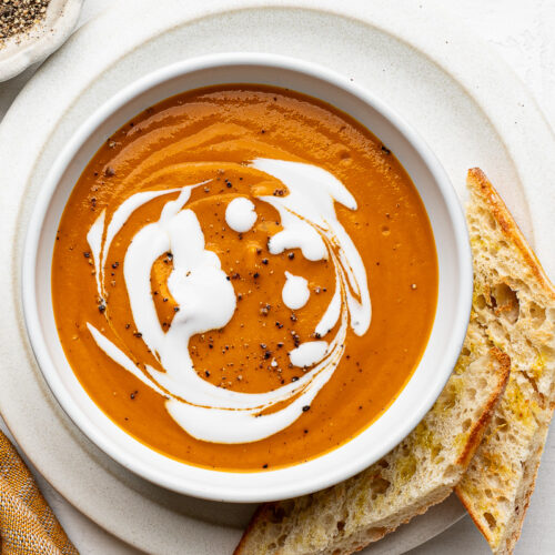 Bowl of roasted vegetable soup with toasted bread on the side.