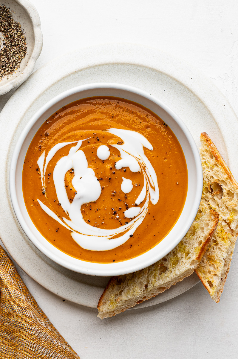 Bowl of roasted vegetable soup with toasted bread on the side.