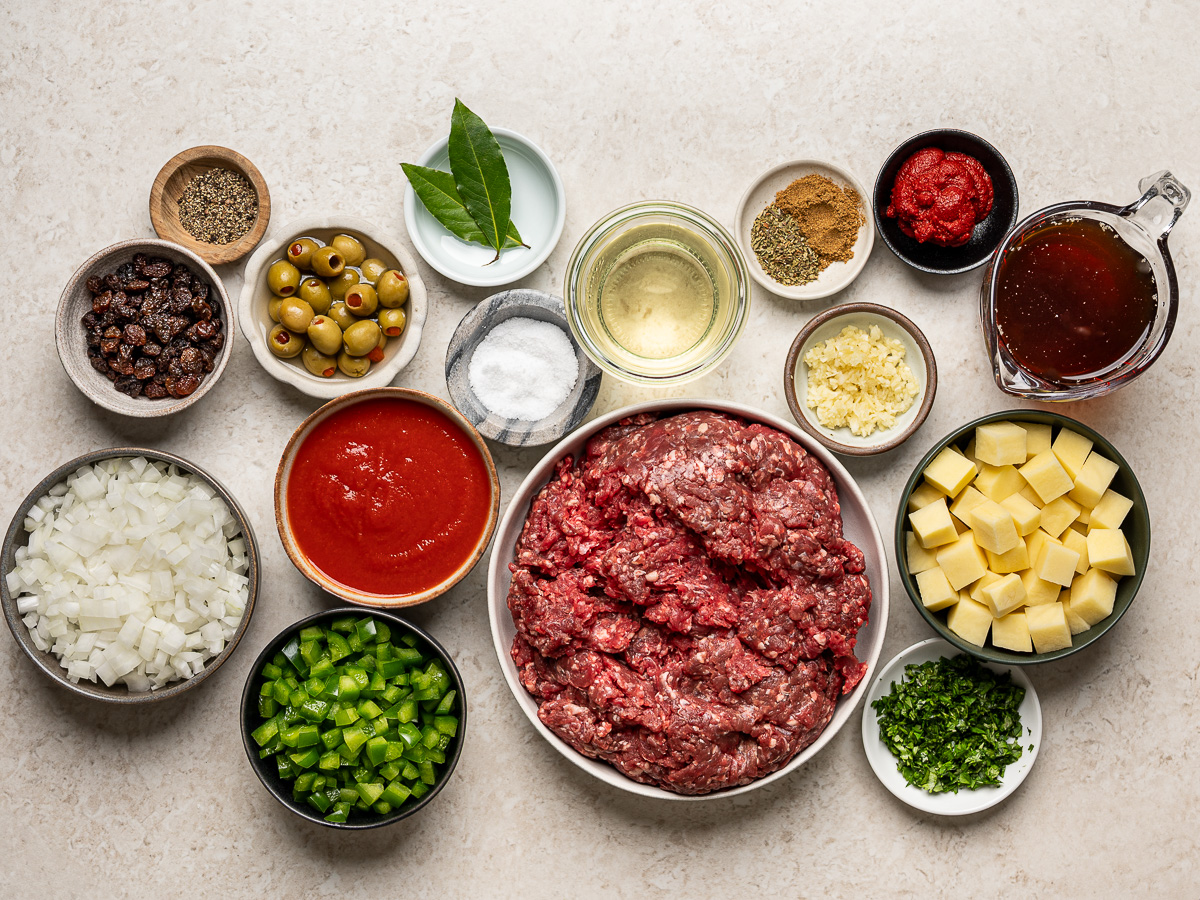 Ingredients for beef picadillo prepared in small individual bowls.