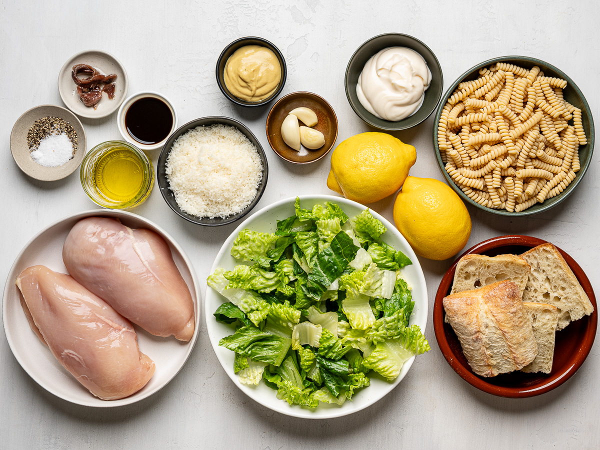 Ingredients for Chicken Caesar pasta salad prepared in individual bowls.