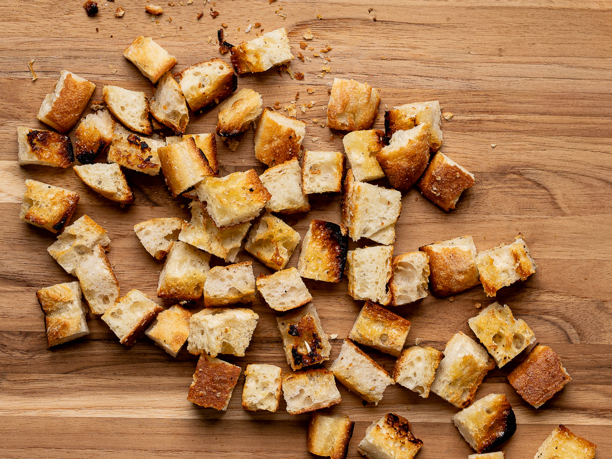 Toasted croutons on wood cutting board.