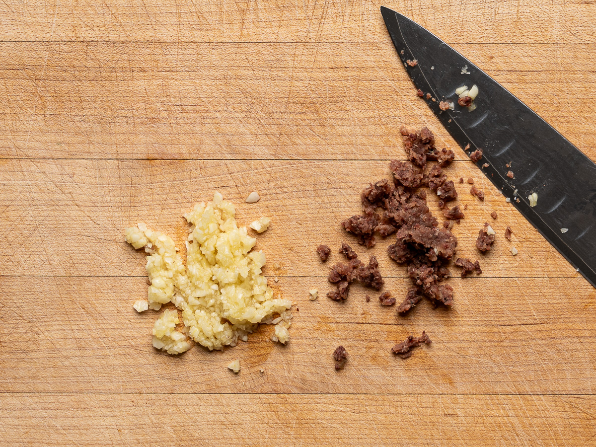 Minced garlic and anchovies on cutting board.