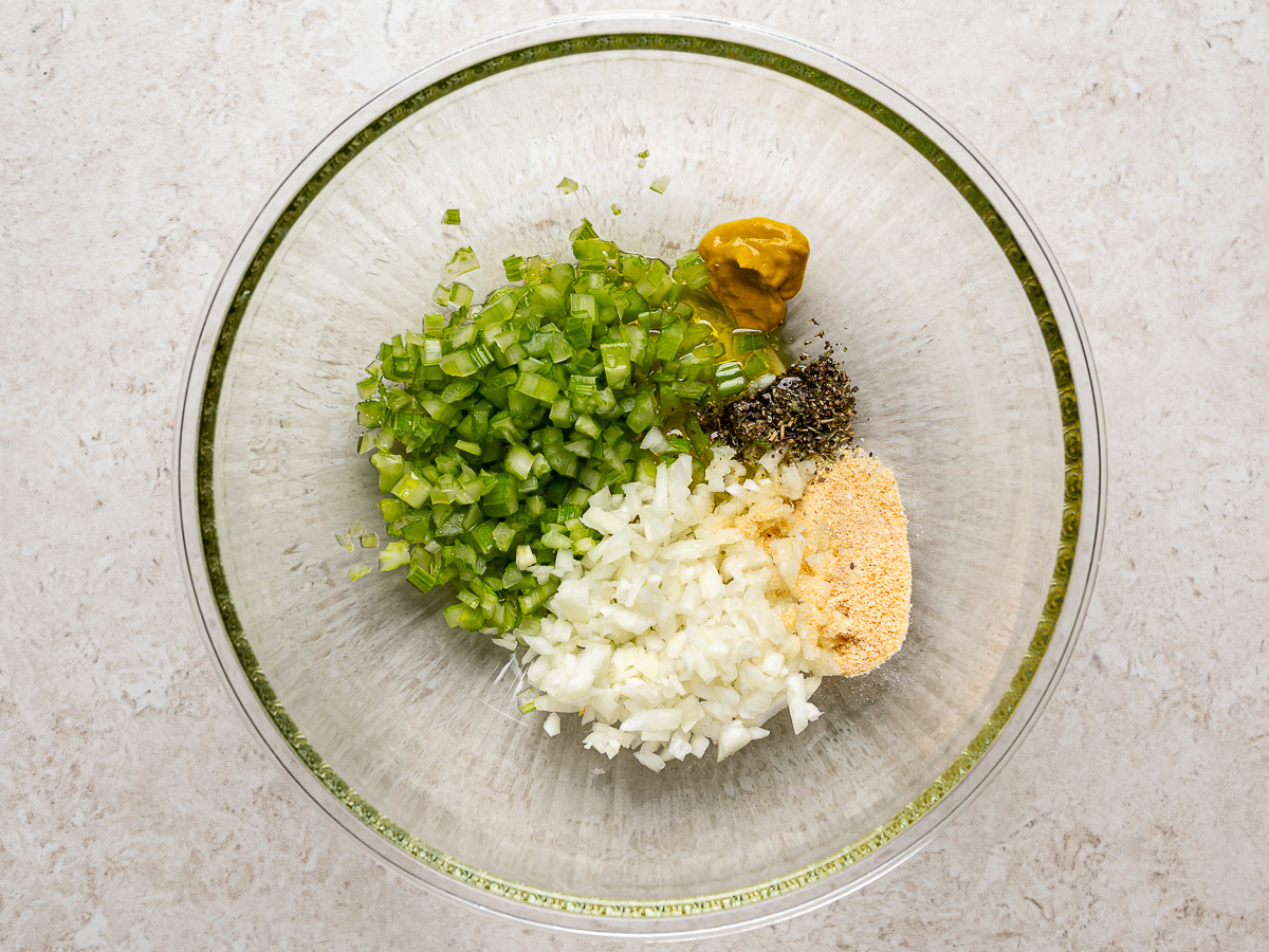 Chopped celery and onion mixture in glass mixing bowl.