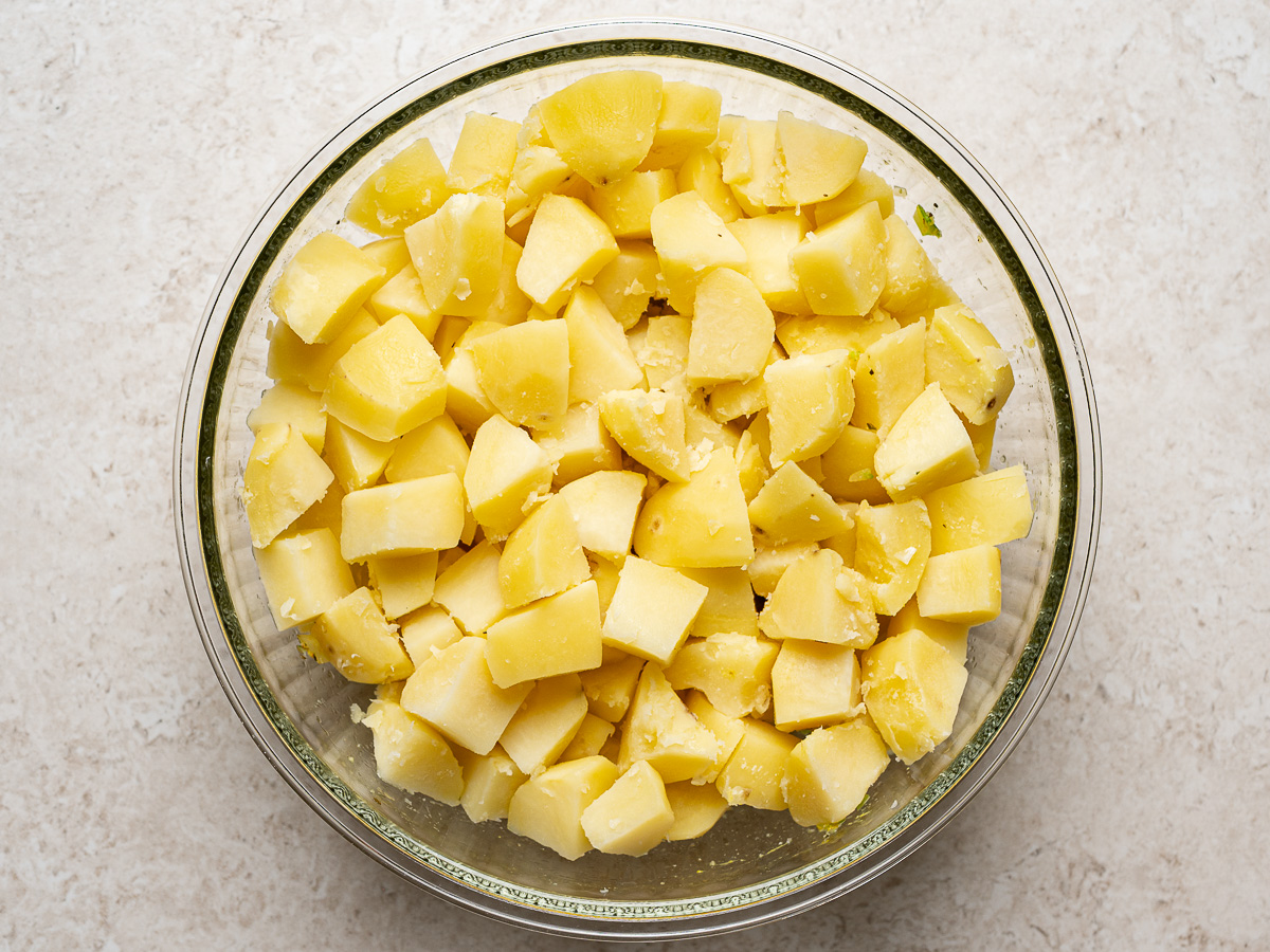 Cooked potatoes in bowl with celery-onion mixture.