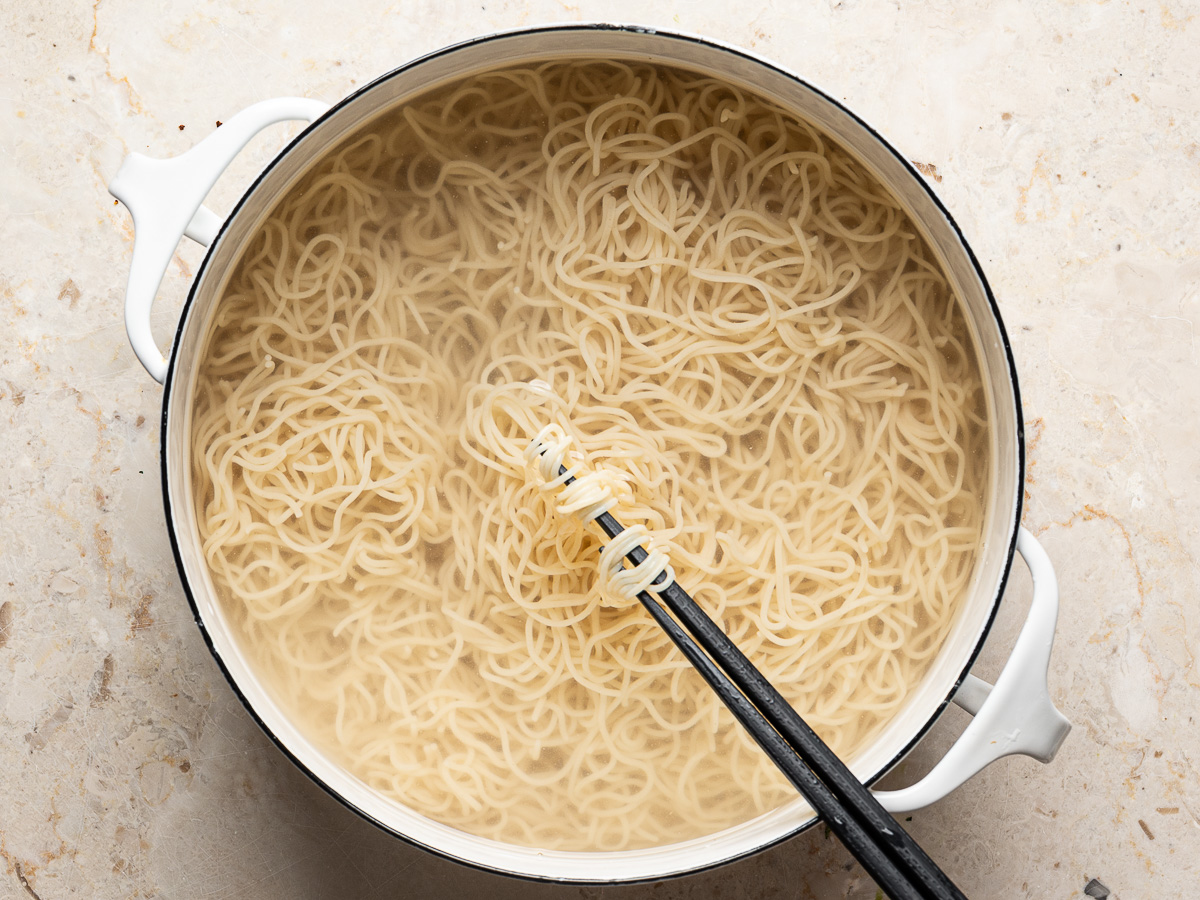 Cooked ramen noodles in large white pot.