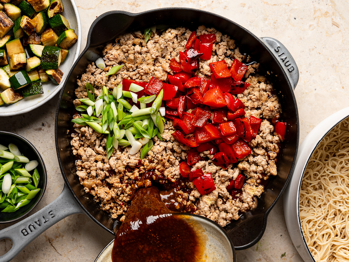 Pouring sauce over ground chicken mixture in skillet.