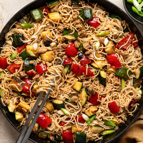 Ramen noodle stir-fry in skillet tossed with ground chicken, zucchini, red peppers, green onions and spicy sauce.