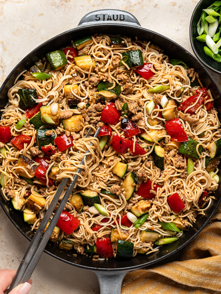 Ramen noodle stir-fry in skillet tossed with ground chicken, zucchini, red peppers, green onions and spicy sauce.