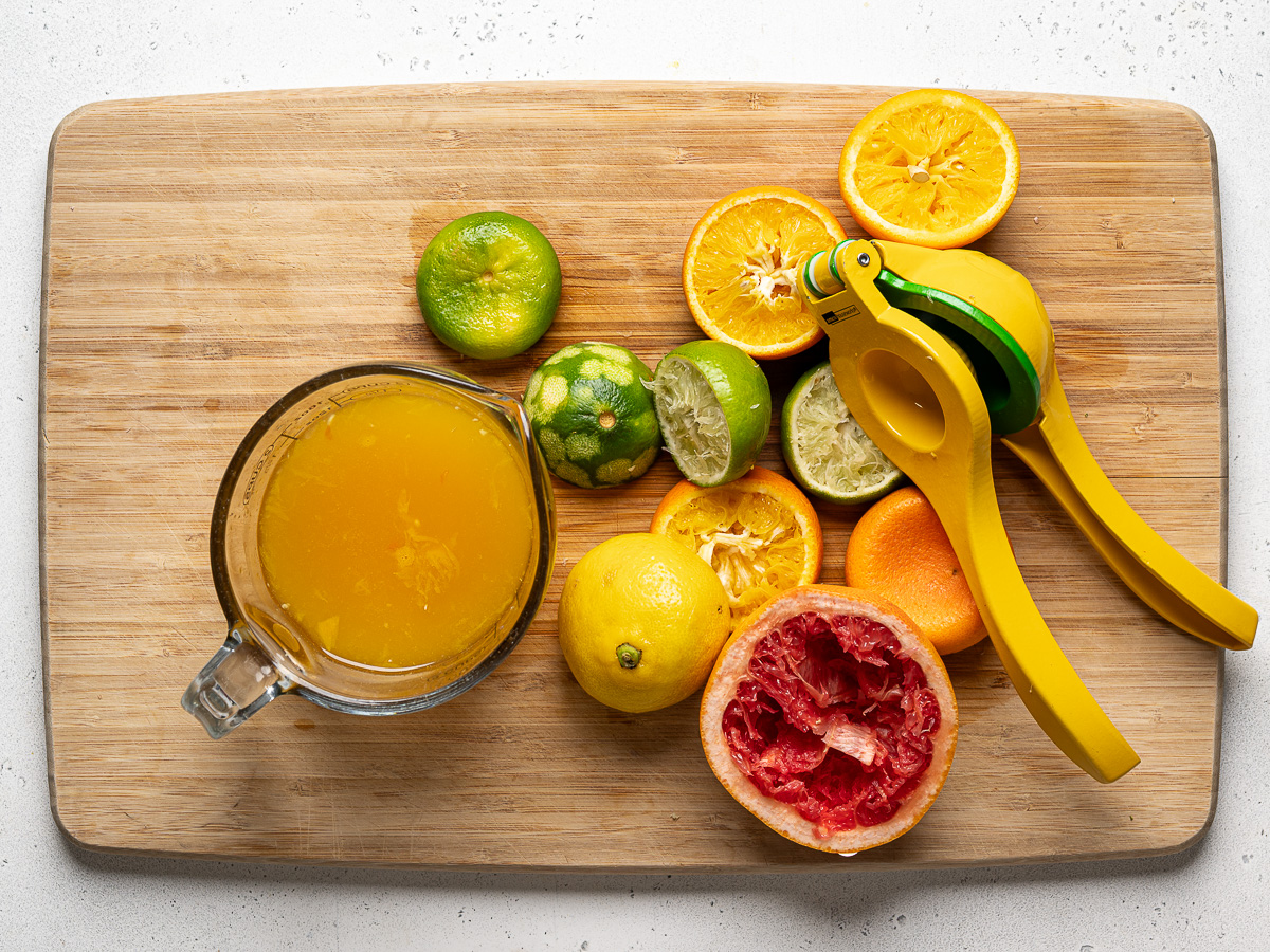 Squeezing all the citrus juice on a cutting board into a glass measuring cup.