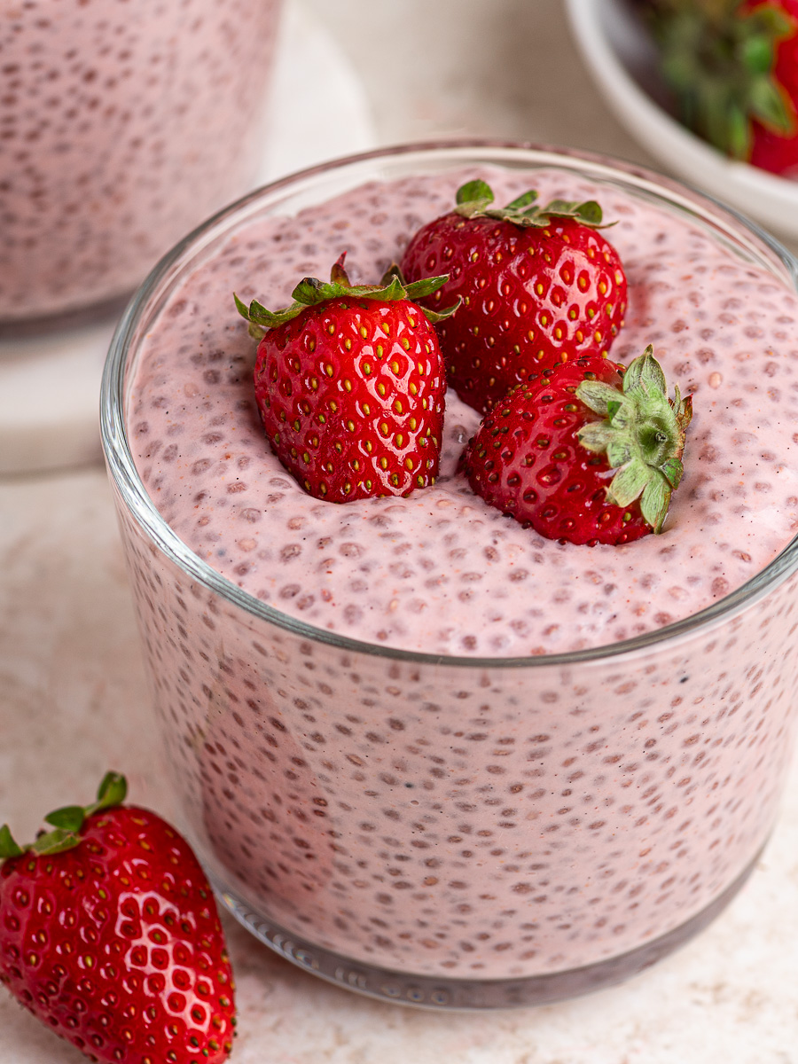 Top view of creamy strawberries and cream chia pudding in a glass container topped with fresh sliced strawberries.