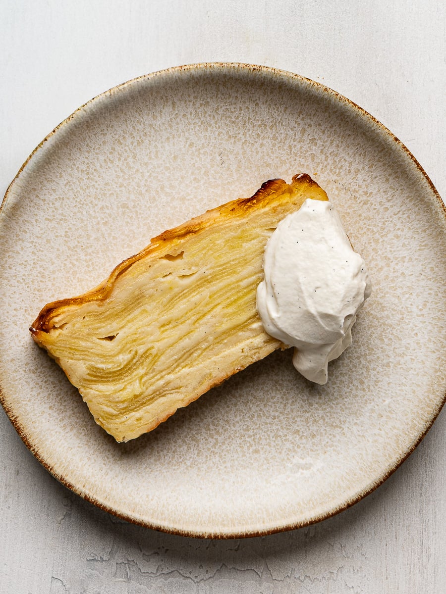 One slice of cake on plate topped with a dollop of whipped cream.