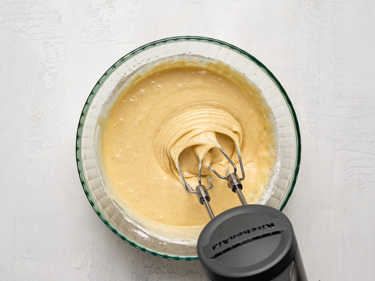 Mixing batter in glass bowl with a hand mixer.