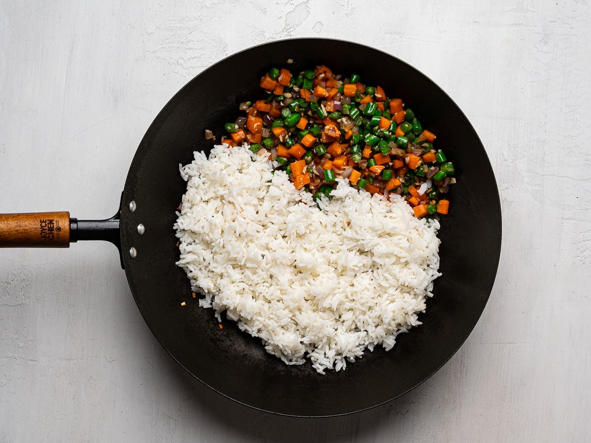 White day-old rice added to wok with softened vegetables.