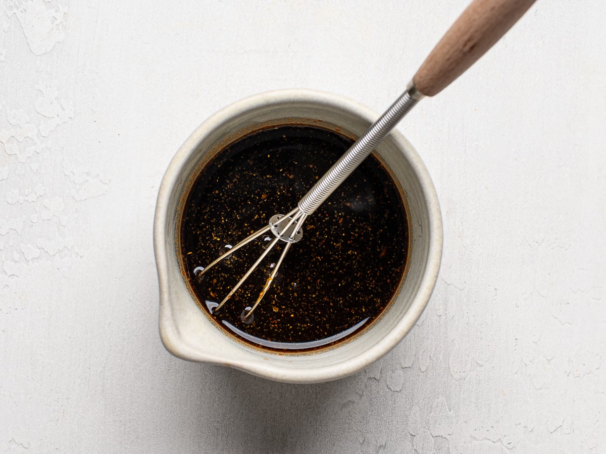 Sauce getting whisked in a small bowl with whisk.
