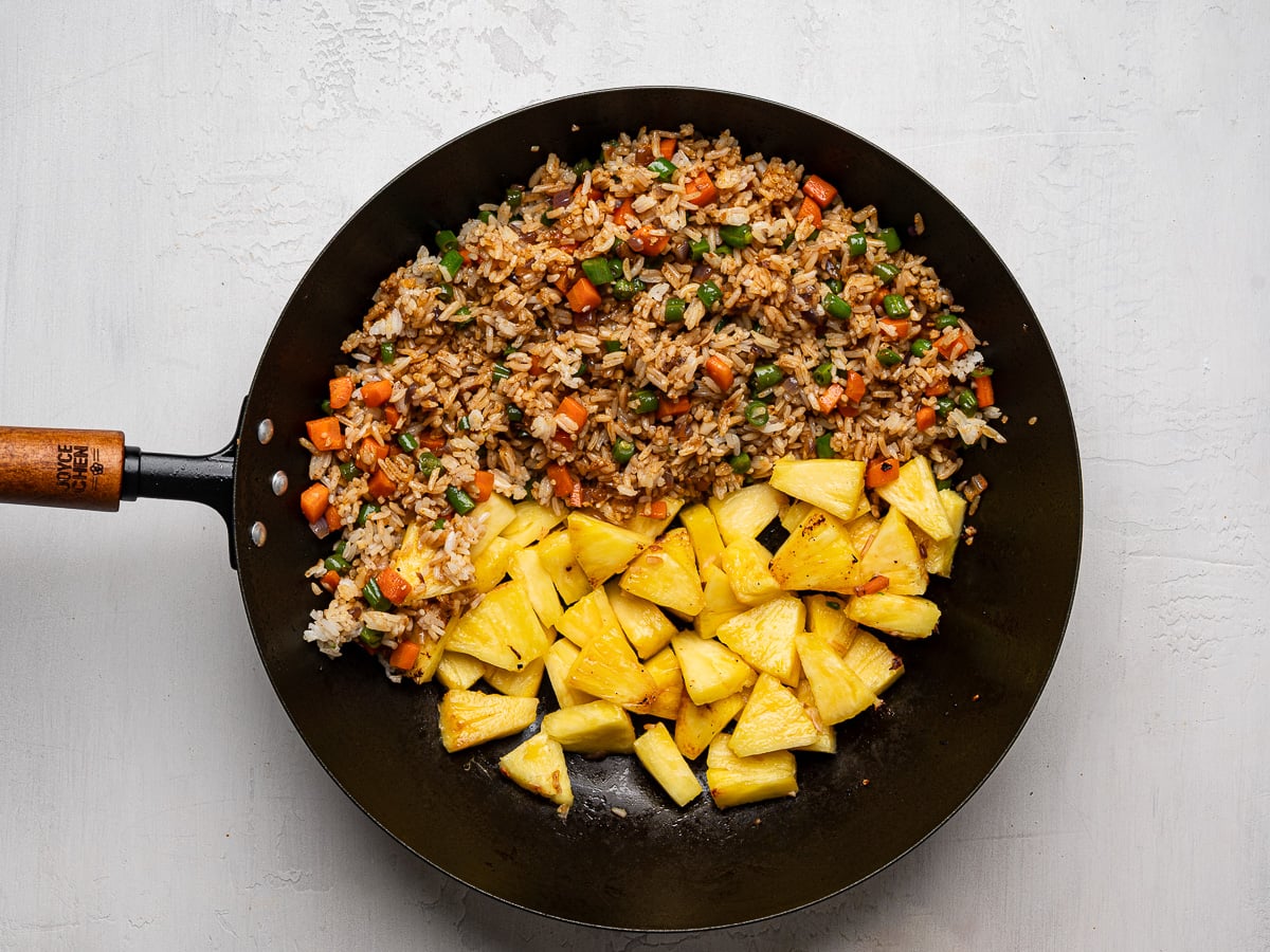 Pineapple pieces added to wok with fried rice.