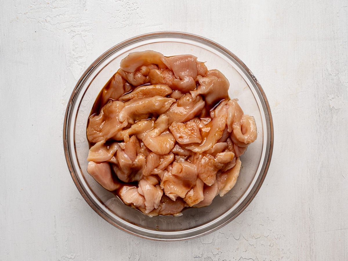 Chicken pieces marinating in glass bowl.
